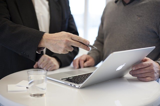 An image showing two people meeting and looking at a laptop. Perhaps this is an example of business analysis in the legal sector?