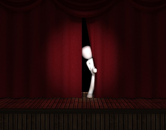 A cartoon image of someone peeking out from behind the stage curtain before a performance.