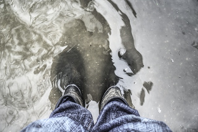 A pair of feet in wellington boots stands in floodwater.