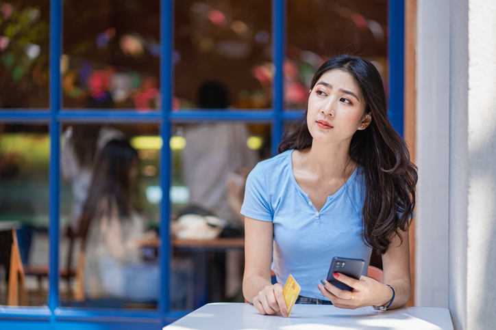 A woman paying by card on her mobile device.