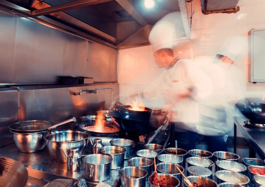 A very busy and hot kitchen, with flames and steam.