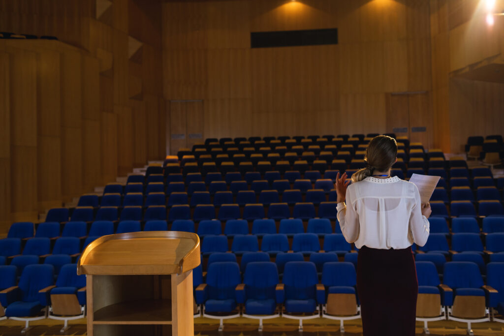 A woman presents to an empty auditoreum.